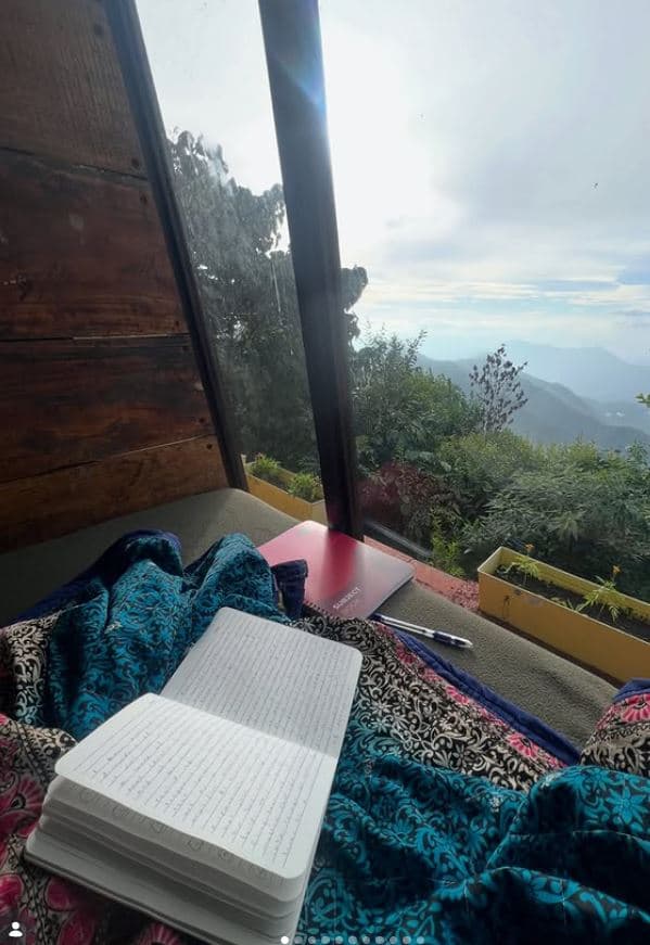 An open notebook on a sill beside a window looking out to the hills