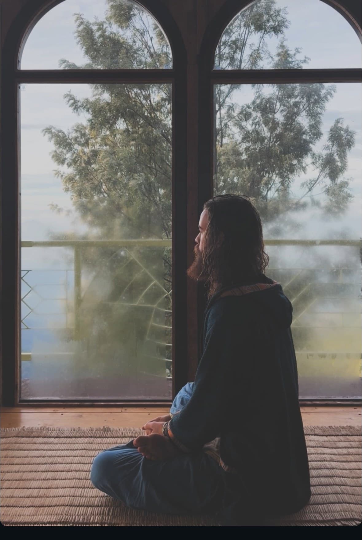 Michael seated in meditation by the arched windows of the hall