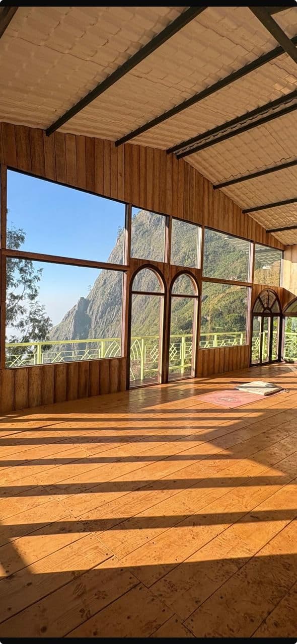 The light-filled yoga hall at Shanti Earth, mountains rising through its tall arched windows