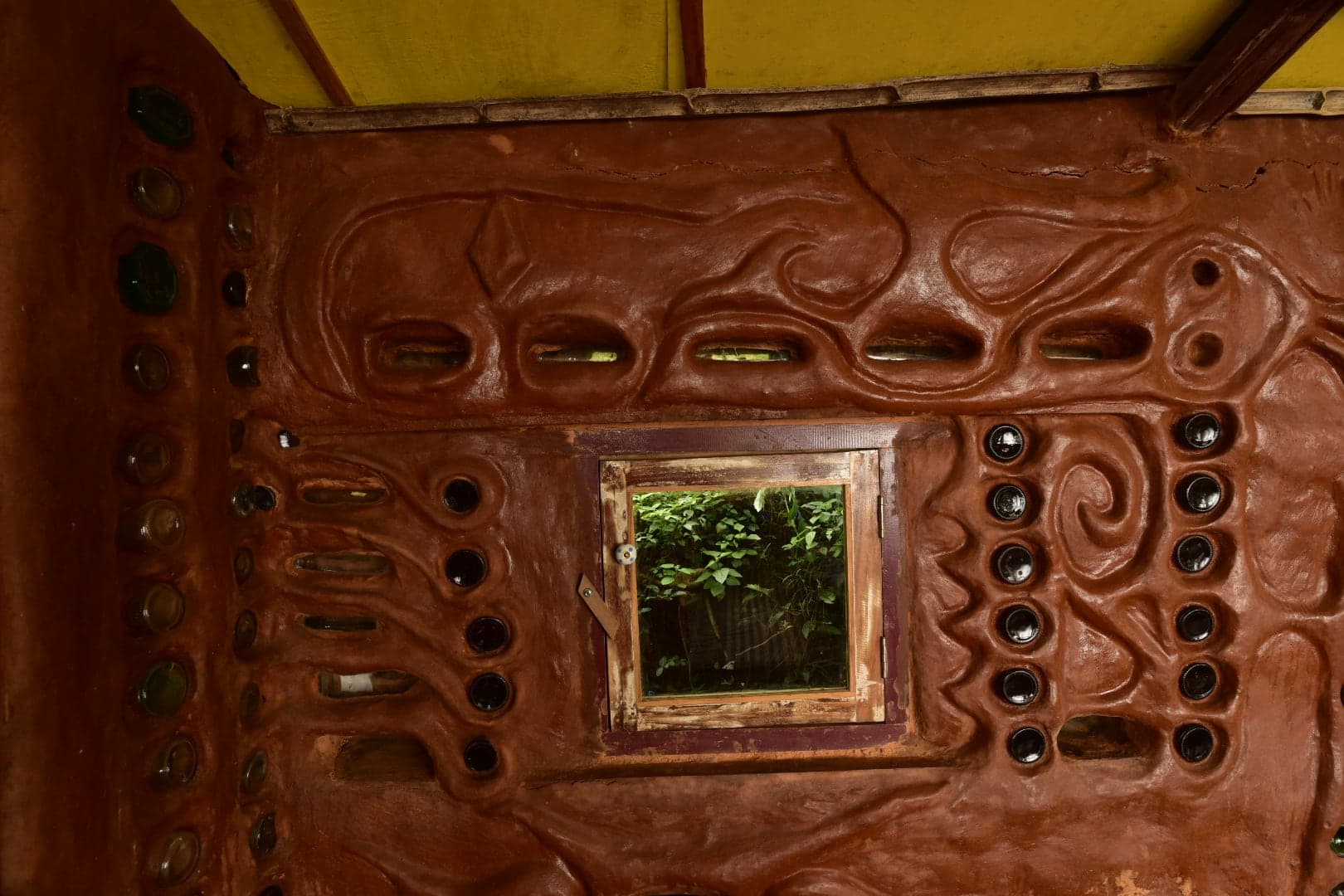 Cob walls set with coloured glass inside Sujata Home