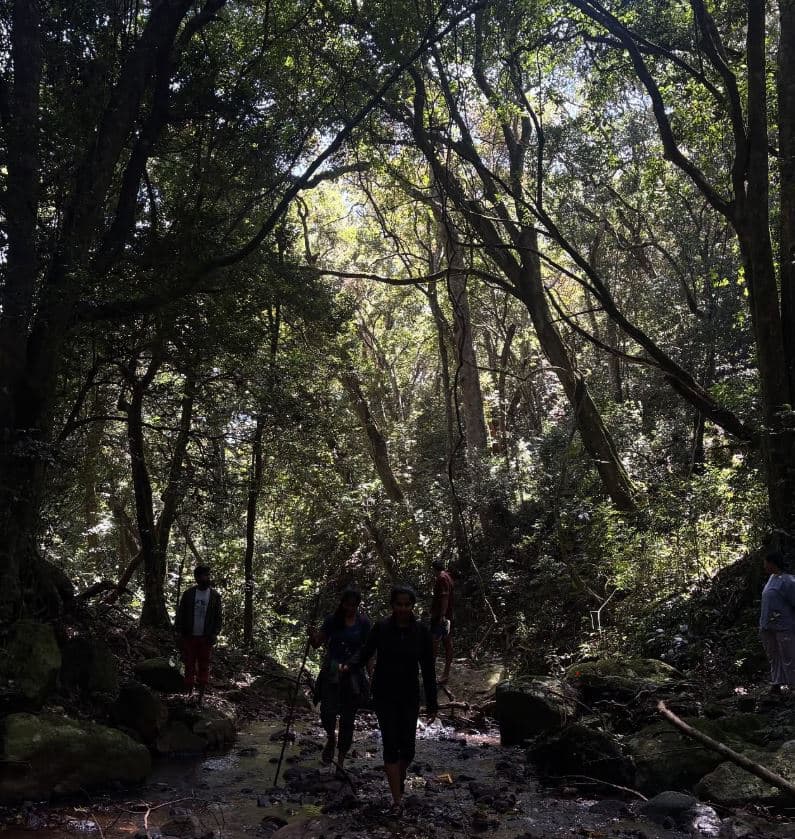 Walkers crossing a river on a trek through the surrounding hills